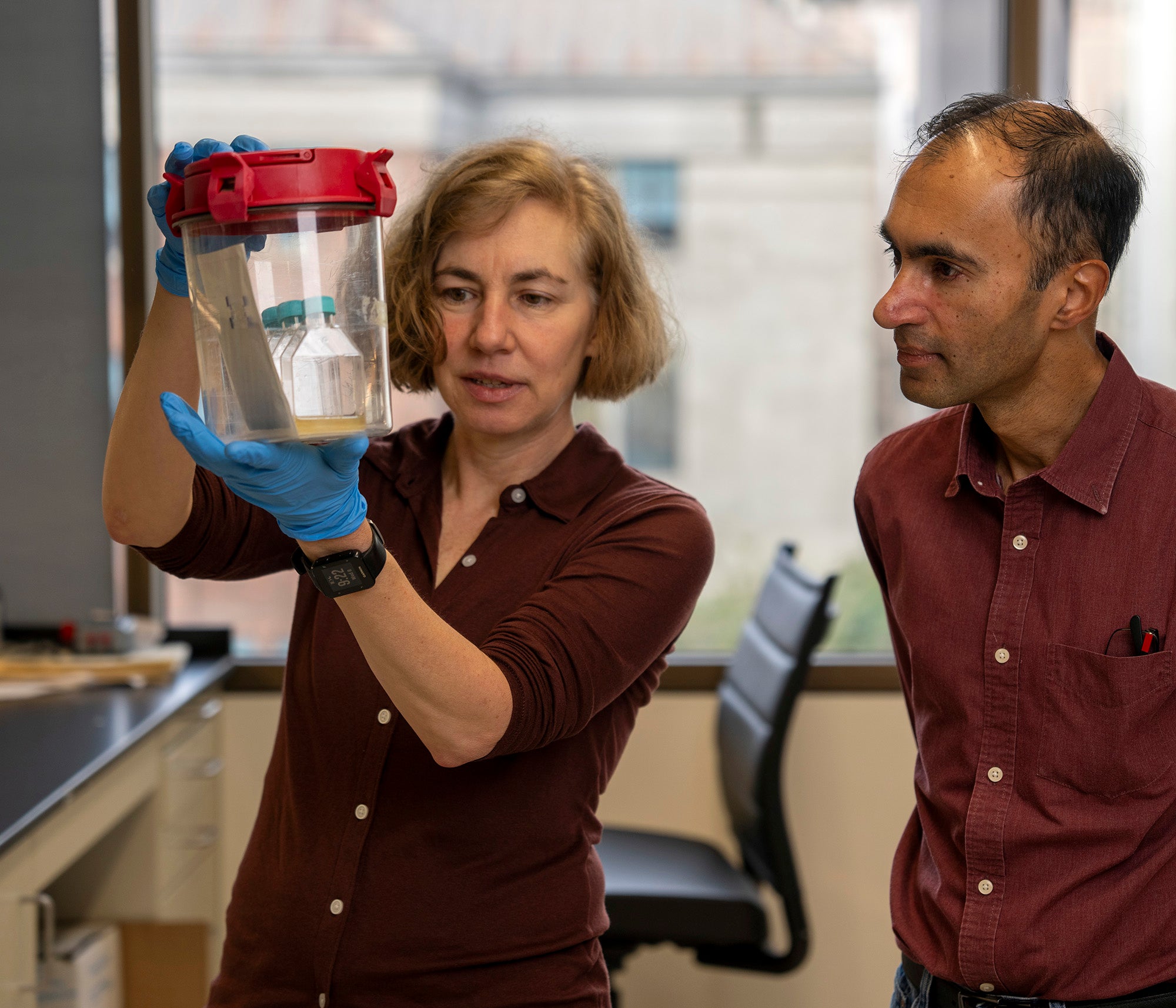 Two researchers look at the contents of a jar.  