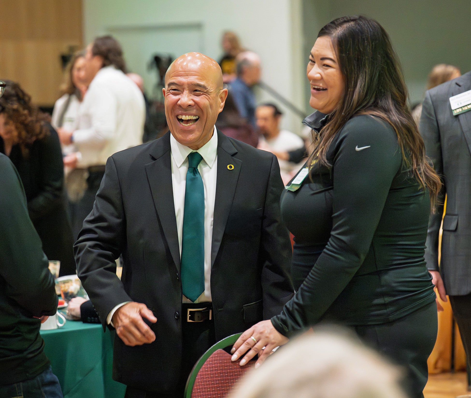 a man and a woman laugh together at an event. 