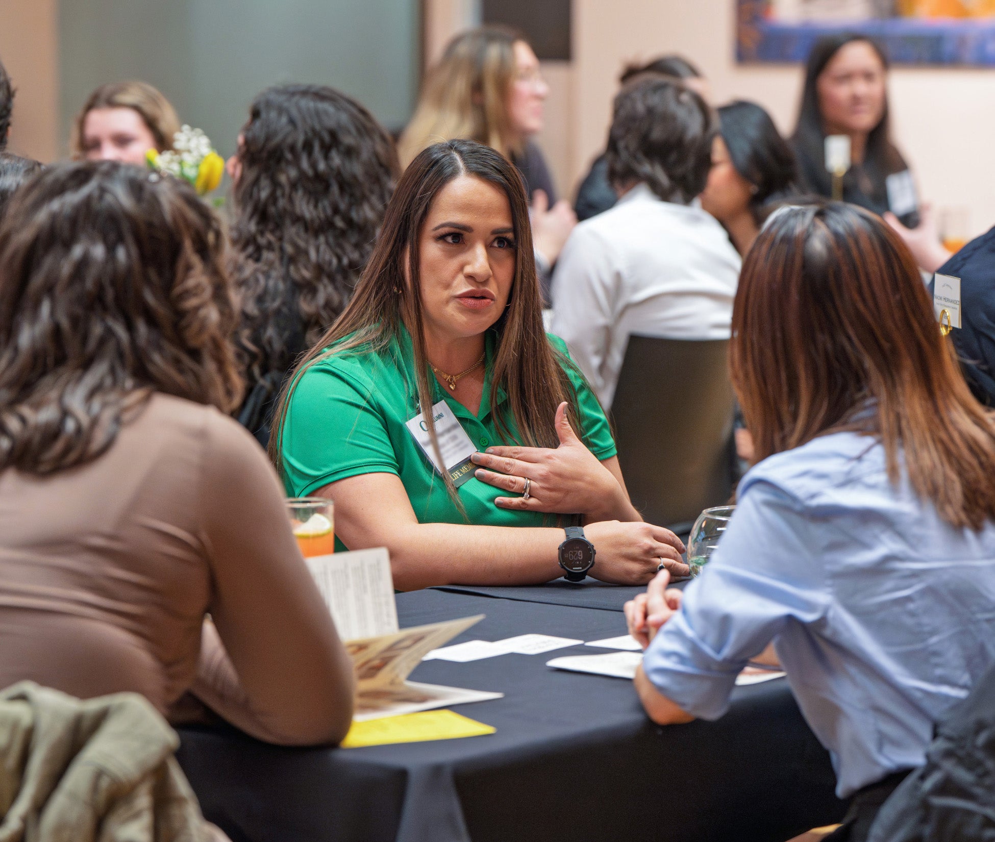 a woman at a table speaks to students at an event