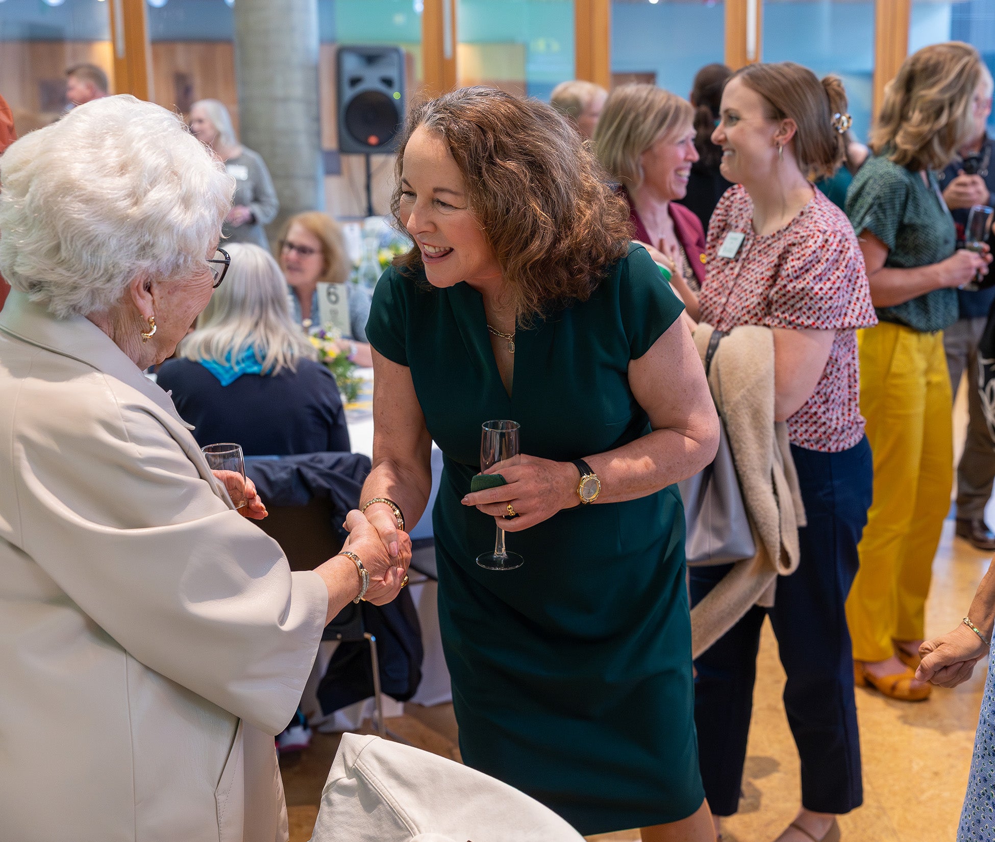 Two women shake hands at an event. 