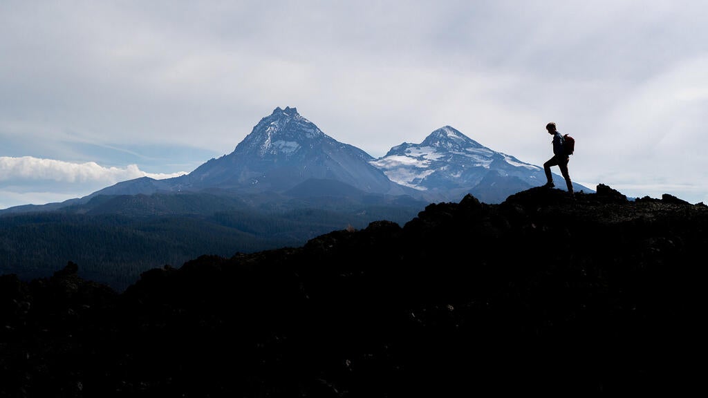 Theo Morganson stands on a ridge with a mountain in the background