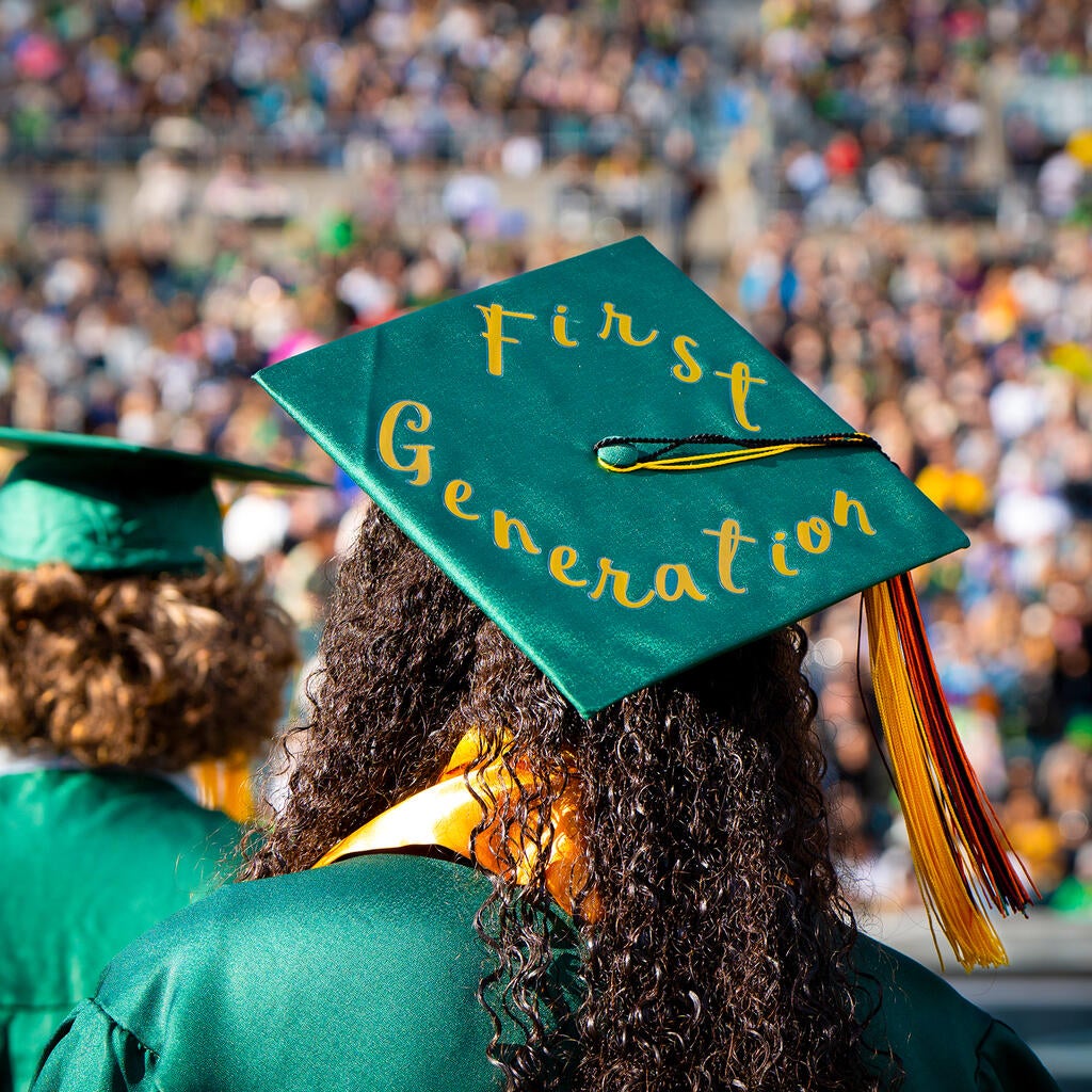 A student wears a mortarboard that reads "first generation." 