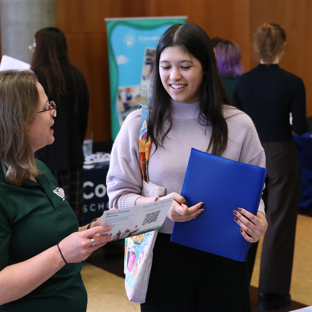 woman talks with another woman at a career fair. 