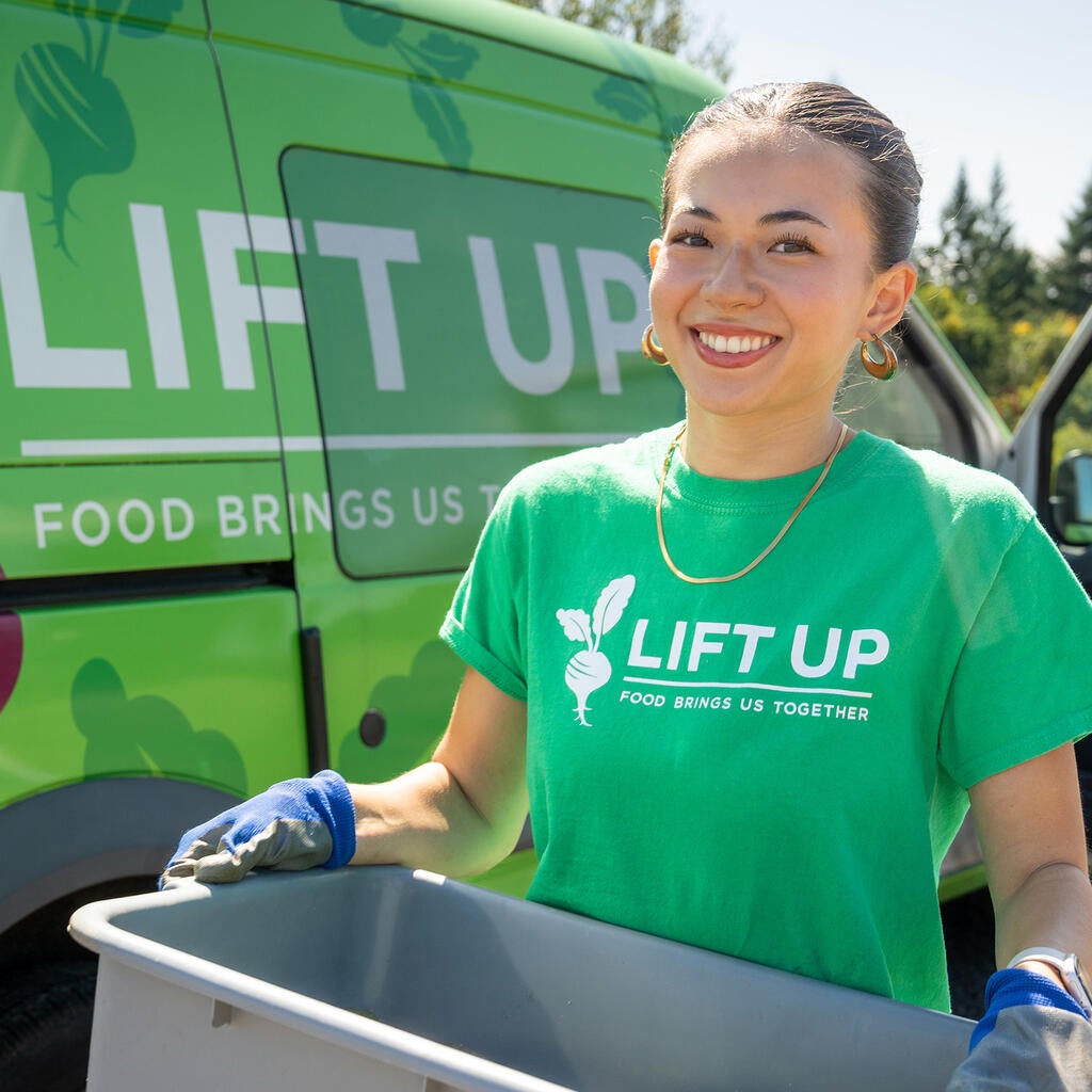 a woman carries a plastic bin near a van. 
